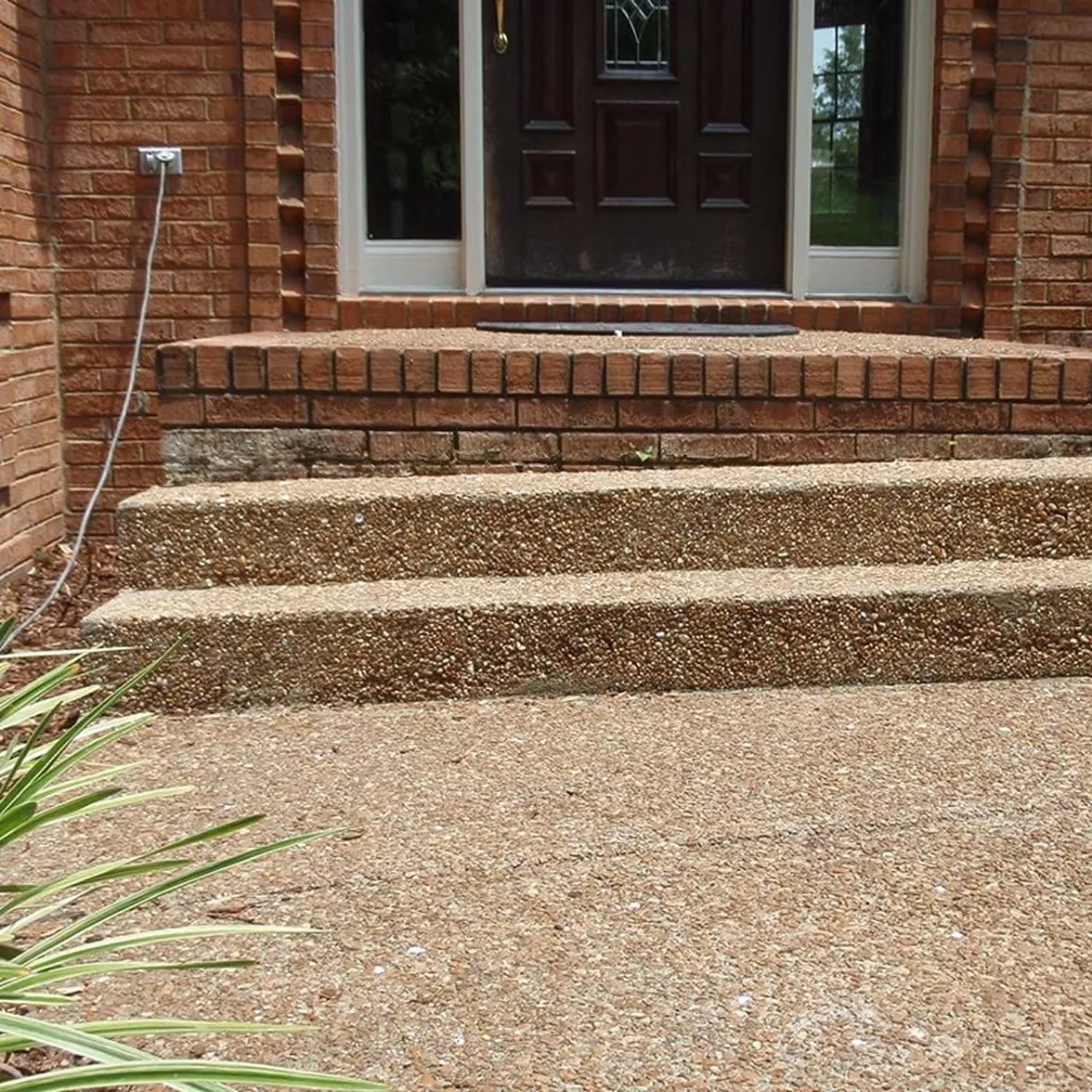 Level, fully supported exposed aggregate entryway steps sitting square against brick doorway.