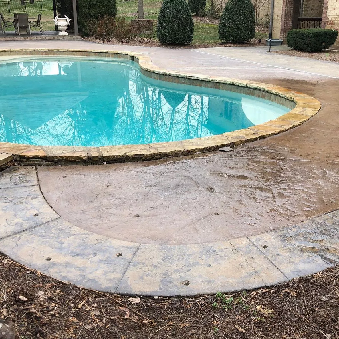 Seamlessly leveled and stabilized decorative stamped concrete pool deck aligned with pool edge.