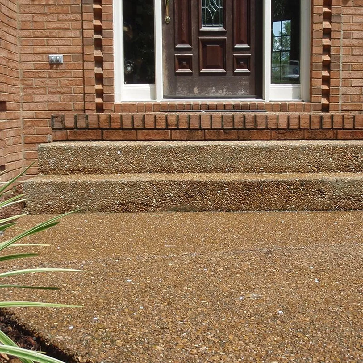 Sinking Exposed Aggregate Steps – Before Foundation Void Fill Exposed aggregate concrete steps sinking and pitching forward away from brick front doorway.